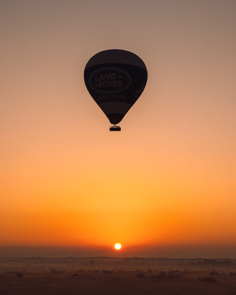 Lever de soleil au-dessus du désert et vue sur la montgolfière Land Rover