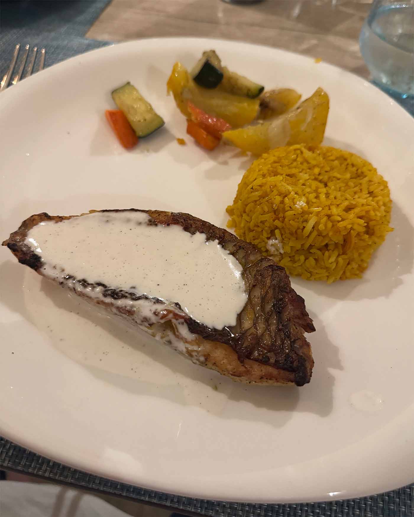 Assiette avec du poisson recouvert d'une crème et du riz jaune