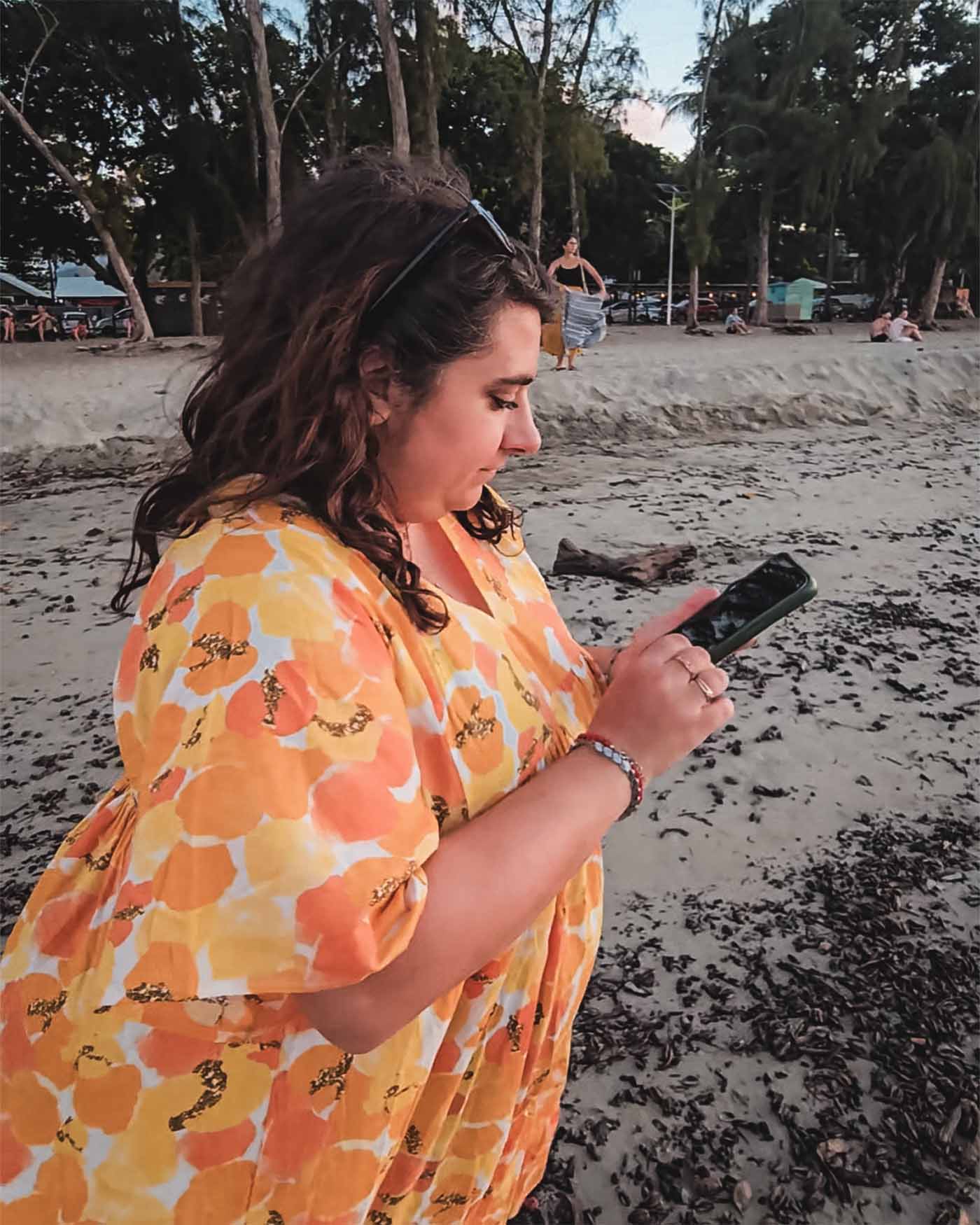 Anne-Sophie tient son téléphone sur la plage